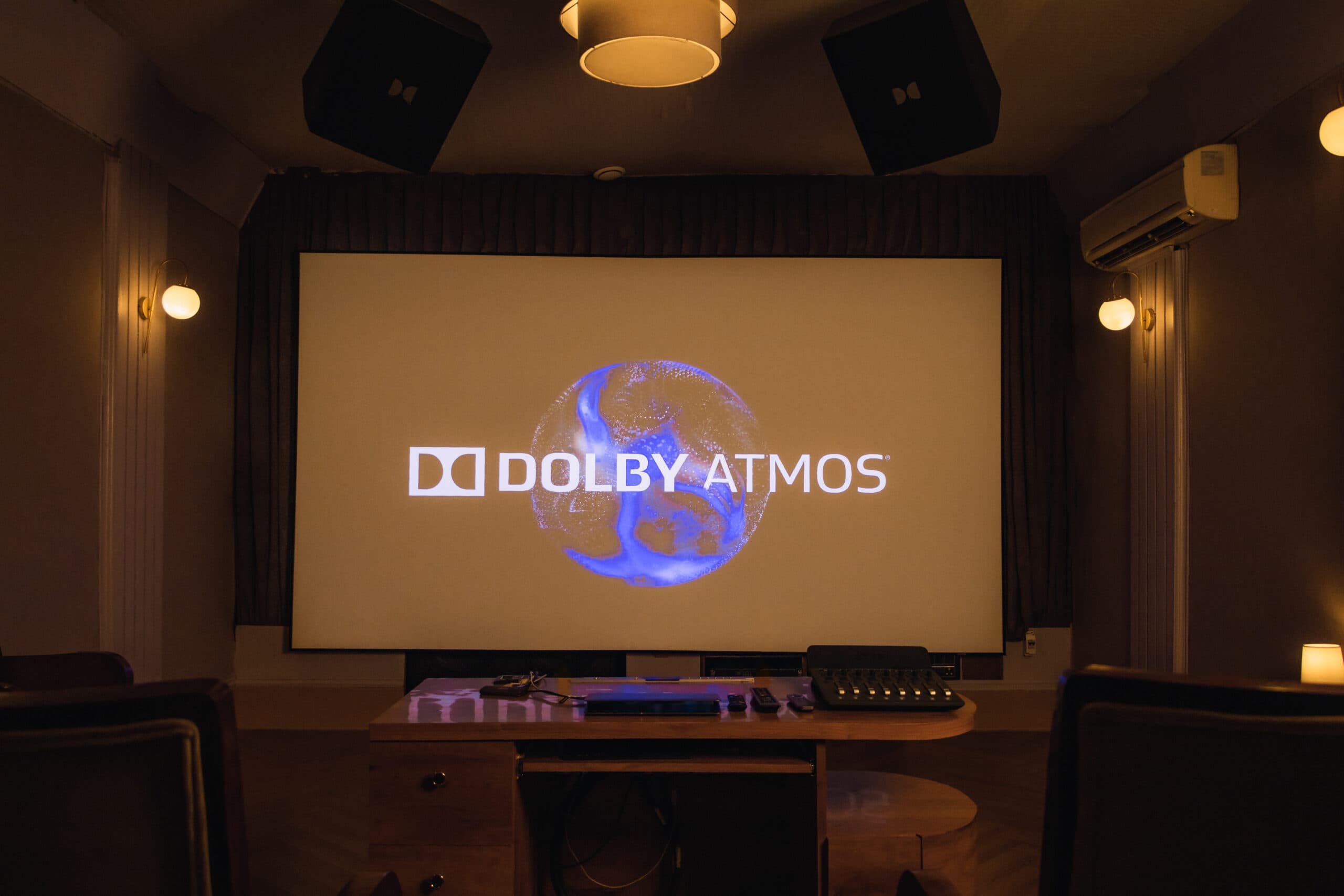 The Dolby Atmos mixstage: a wide projection screen showing the Dolby Atmos logo, ringed by overhead and side speakers