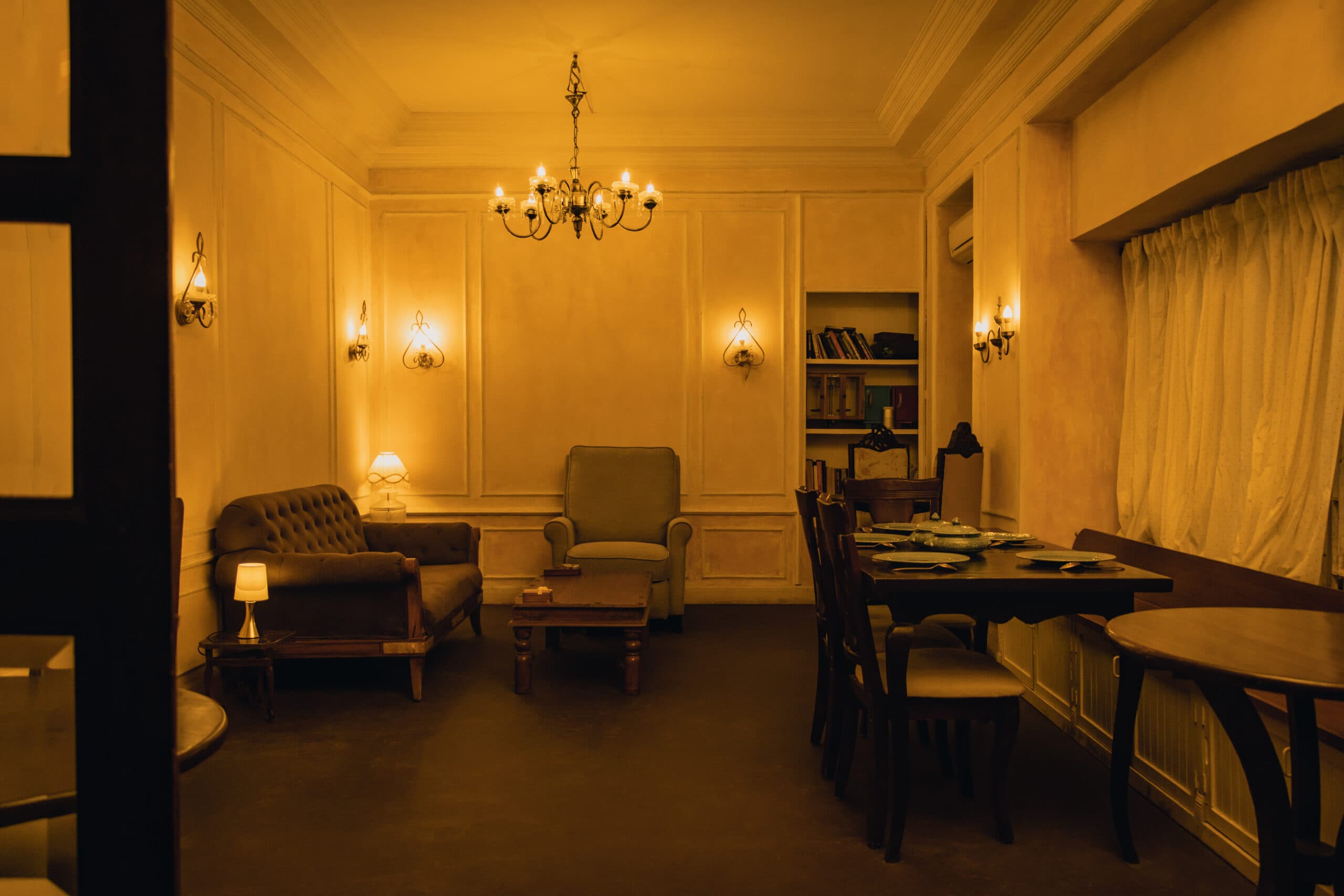 The lounge — panelled walls, a crystal chandelier, chesterfield seating and a laid dining table