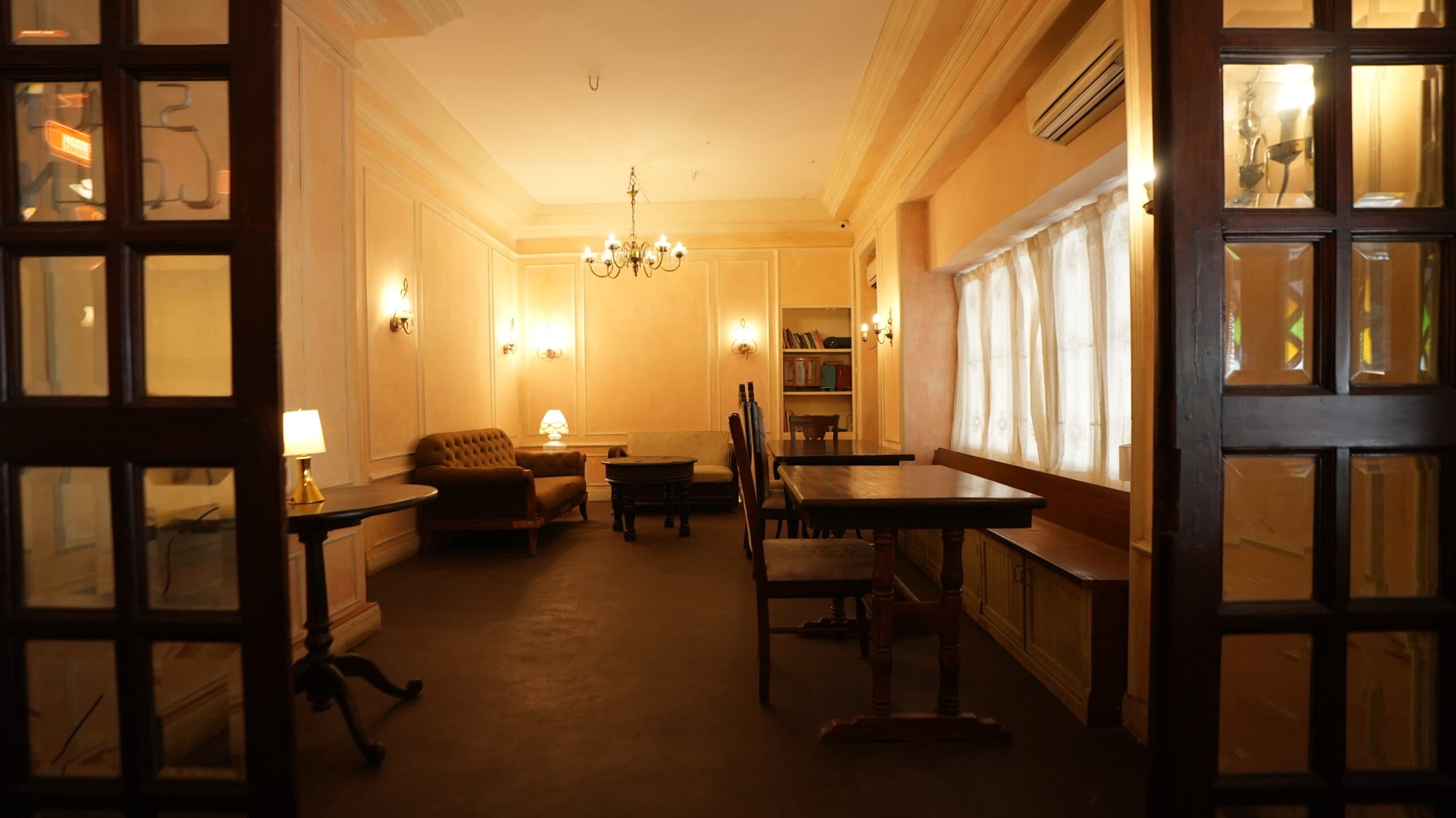 The Sound Lounge: panelled walls, a chandelier, a chesterfield sofa and long wooden tables