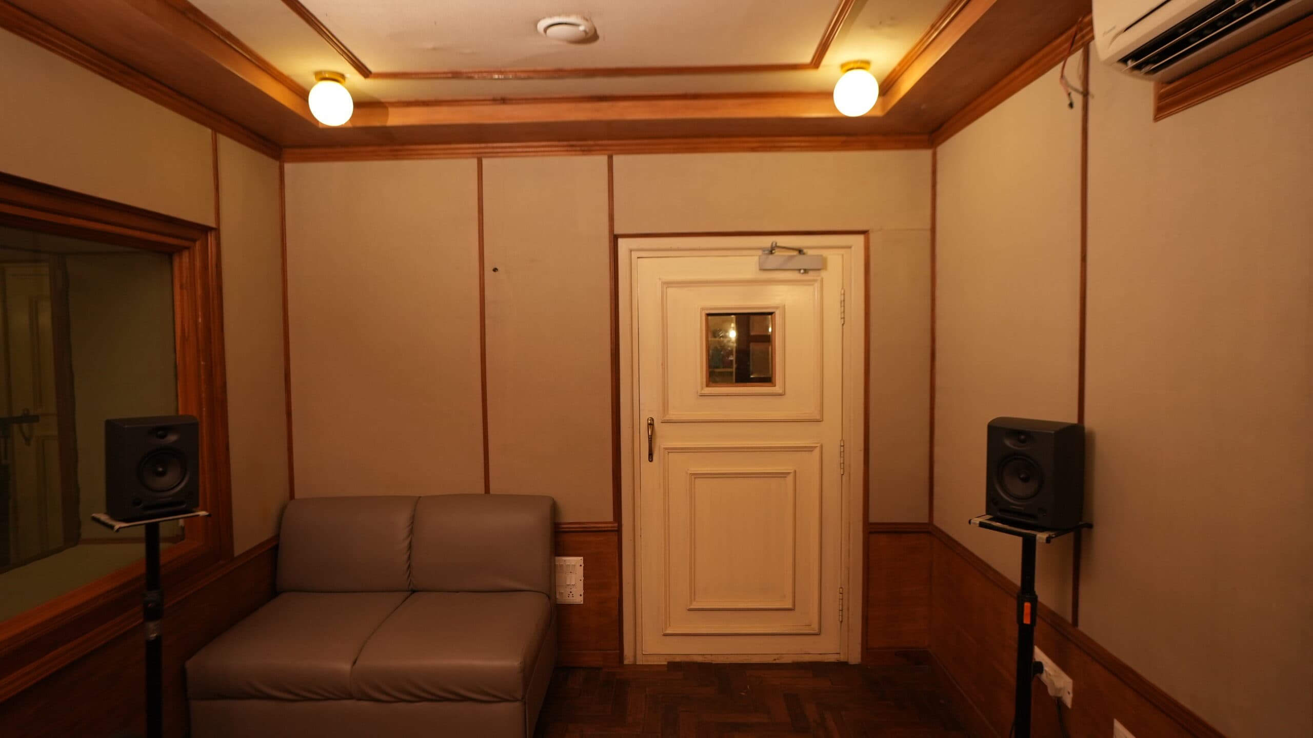 Inside the recording booth: a leather bench between two monitor speakers on stands