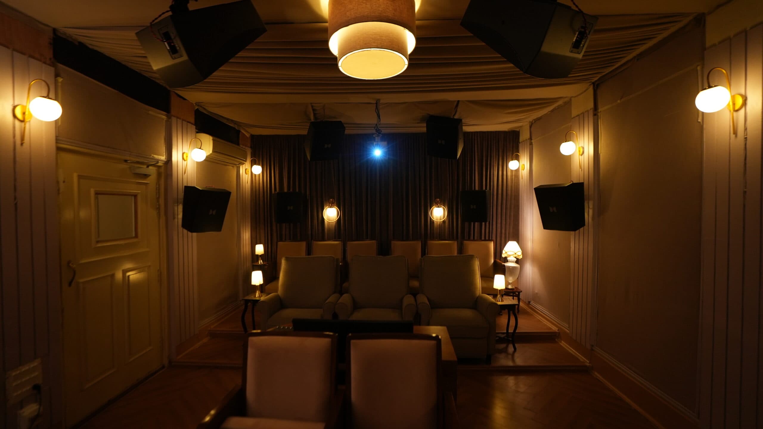 The preview theatre at night — rows of upholstered seats, surround speakers on every wall and a projector beam overhead