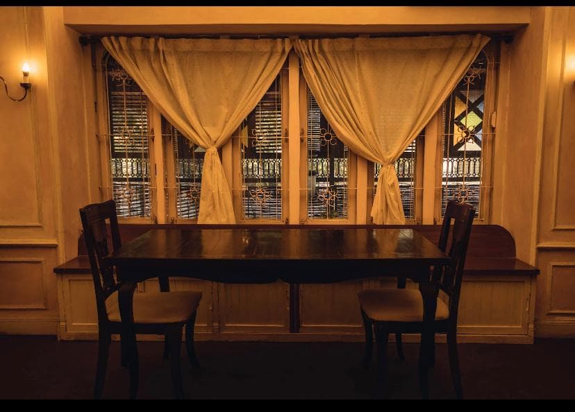 A table for two set against a curtained window with wrought-iron grilles