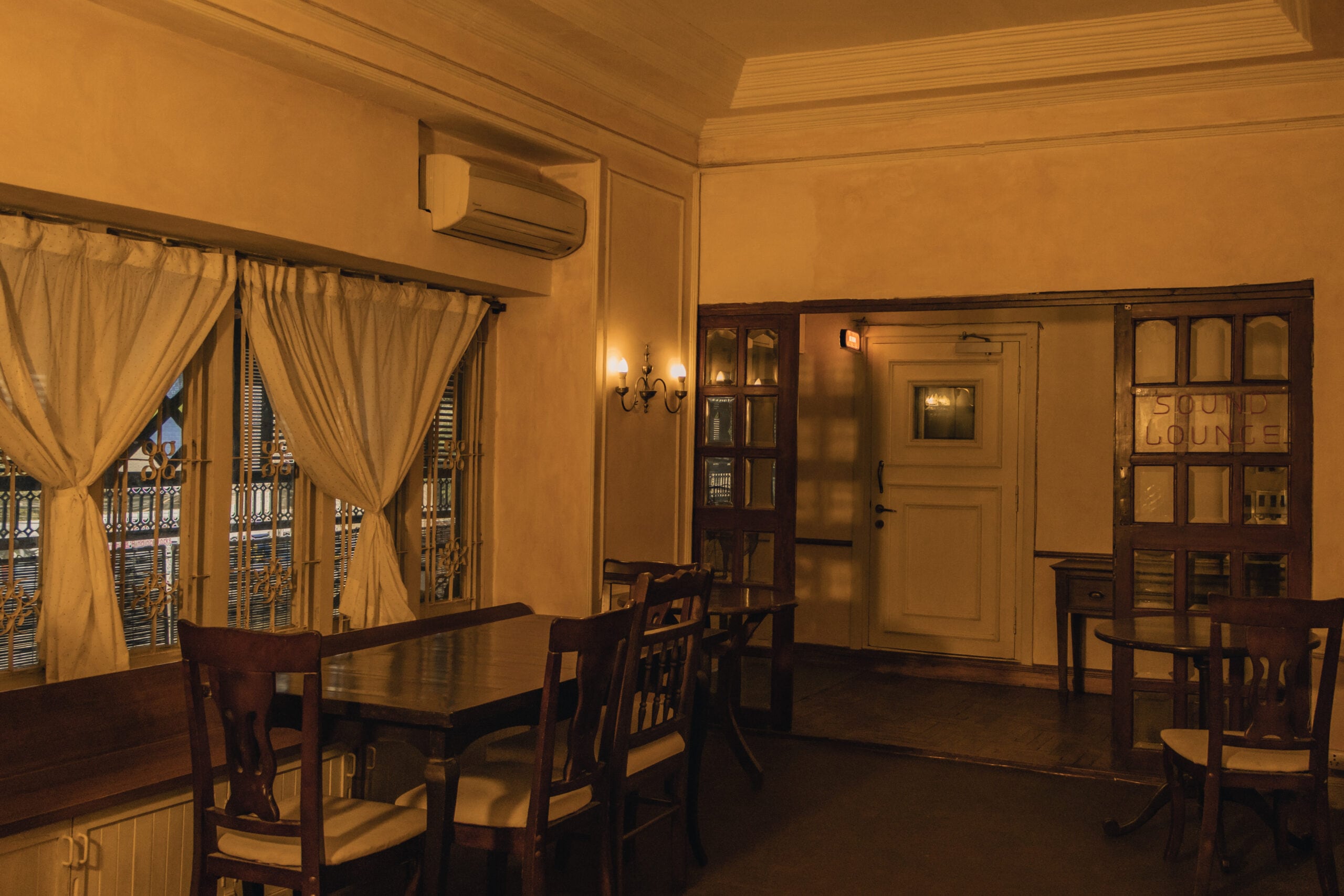 The café and lounge with long dining tables, lace curtains and the etched Sound Lounge doors