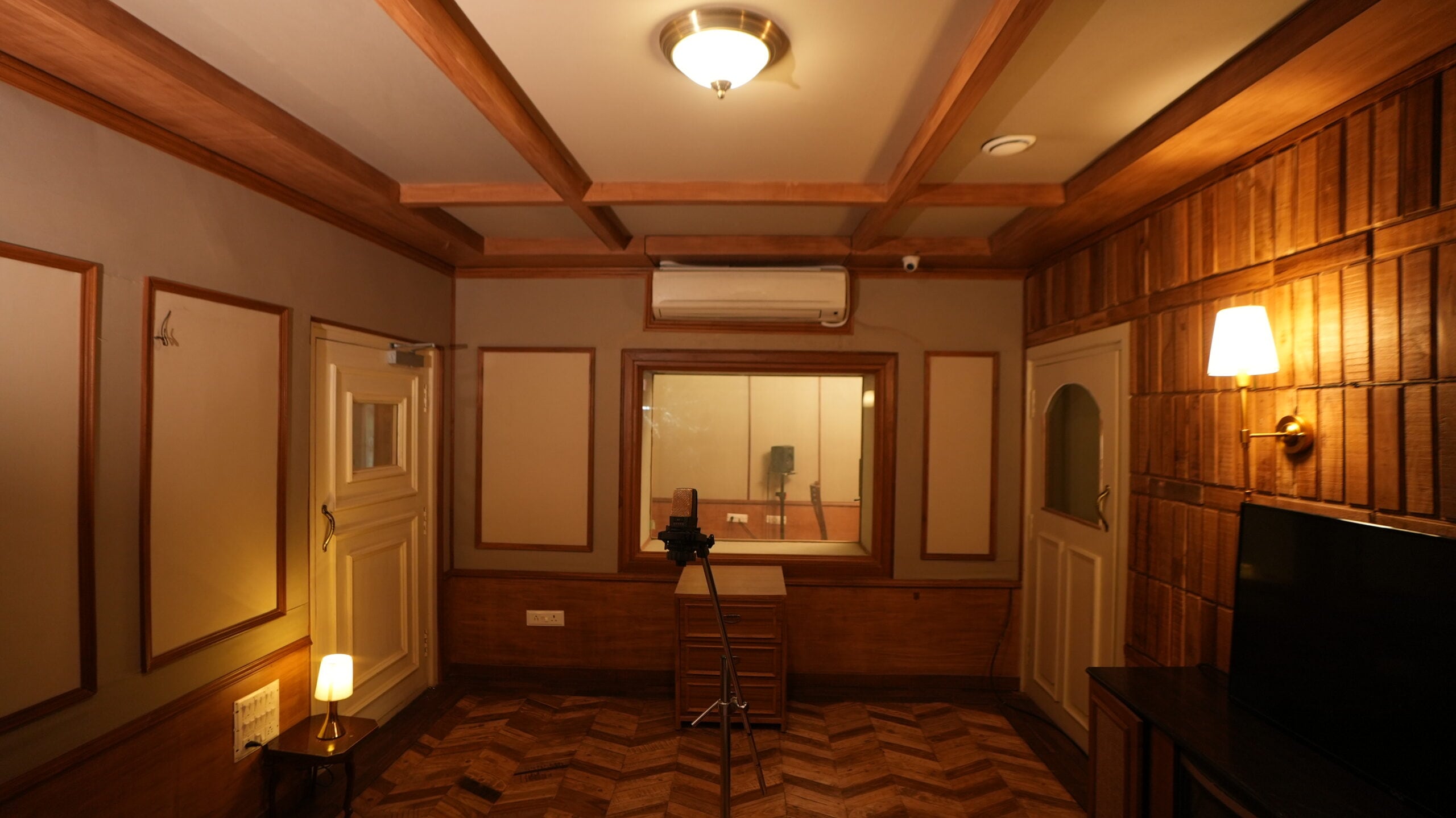 ADR room with a viewing window into the booth and a microphone on a stand