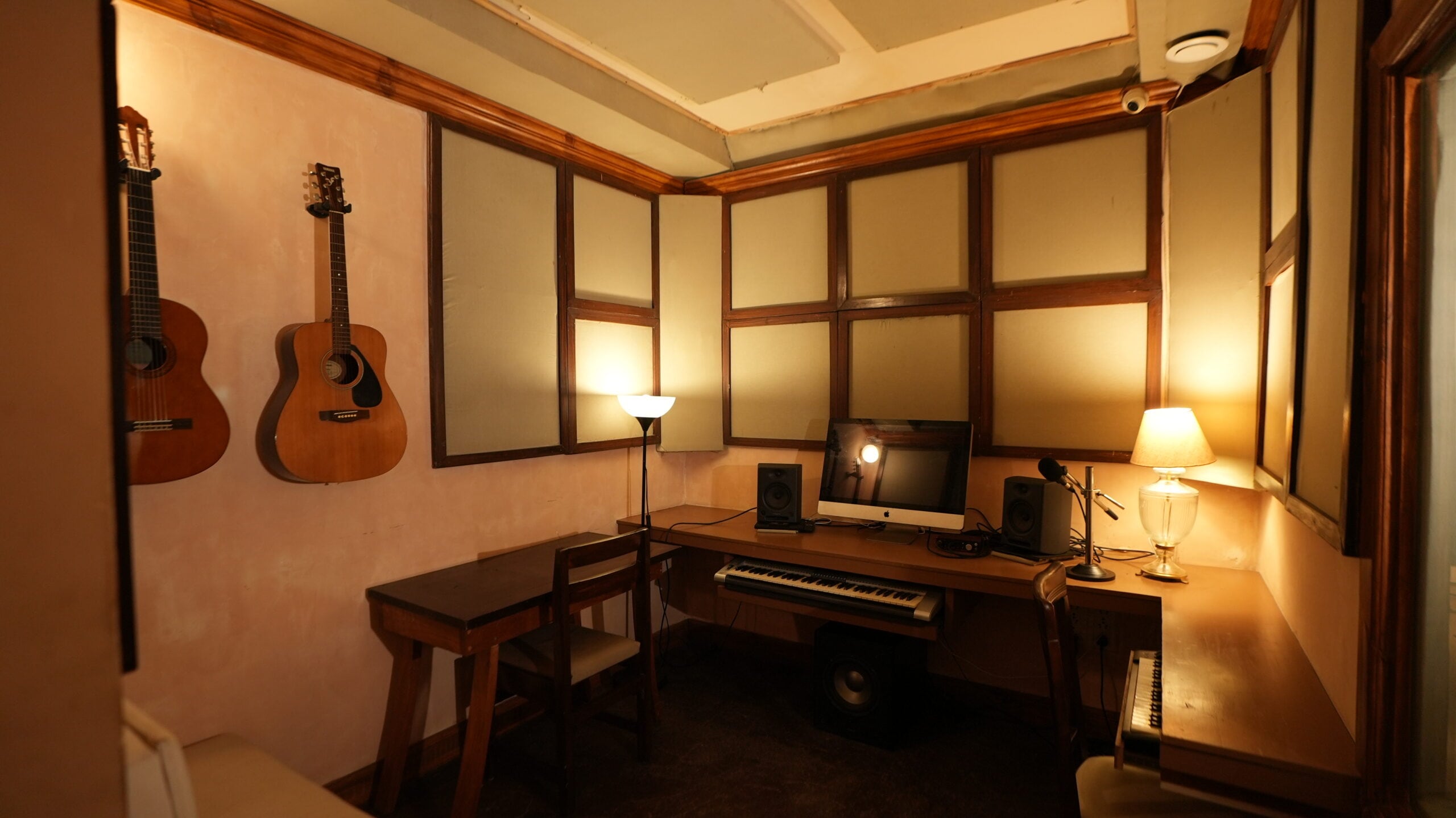 The music room with two acoustic guitars on the wall, an iMac, keyboard and monitors