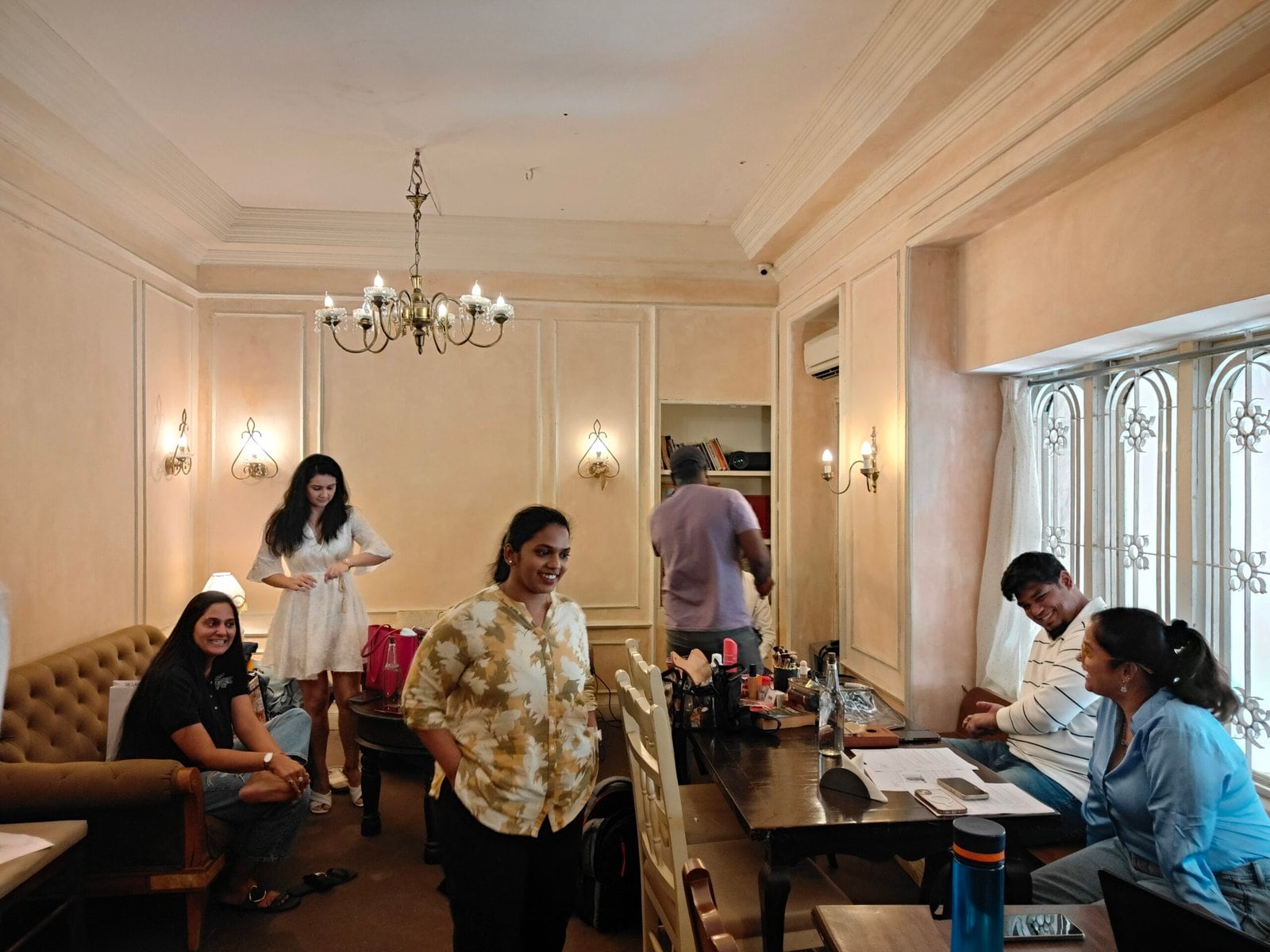A production team at work in the lounge, gathered around tables under the chandelier