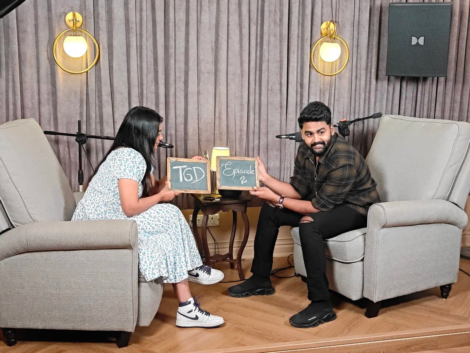 Two podcast hosts holding chalkboard signs on the podcast set